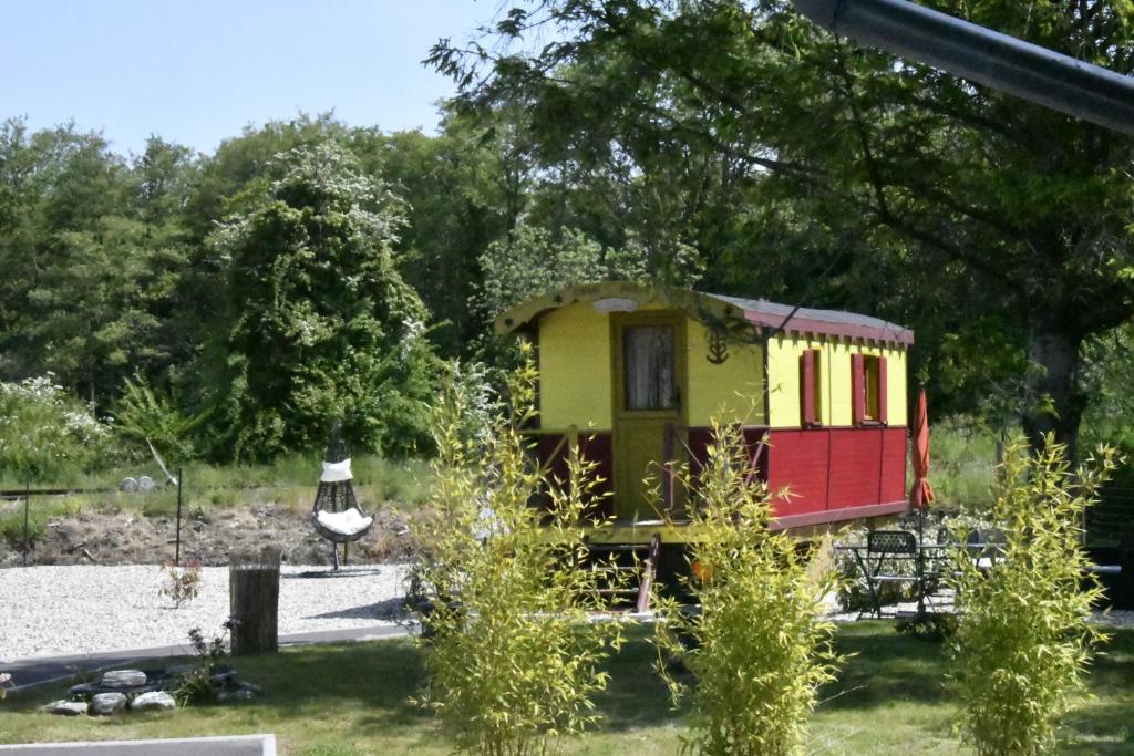 um pequeno comboio de brinquedo num quintal com árvores em Roulotte pour une nuit en amoureux tout équipée.. em Noyelles-sur-Mer