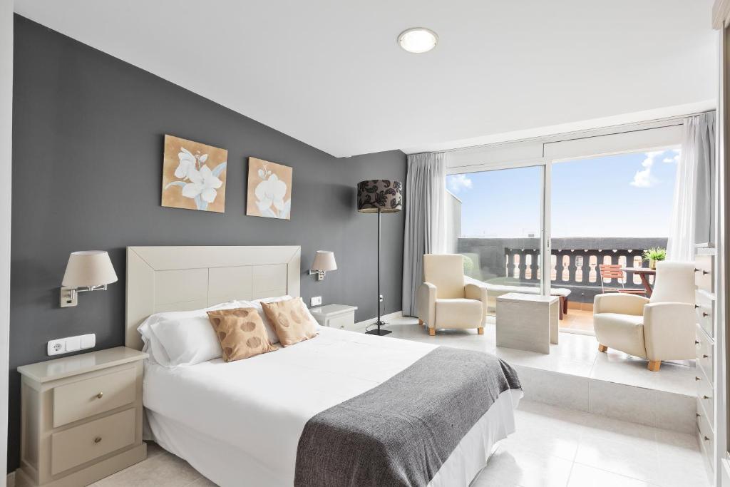 a bedroom with a white bed and a balcony at Andreas Apartments in Tarragona