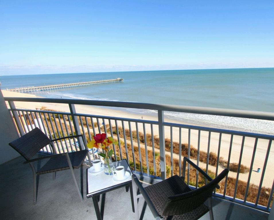 Oceans One Resort في ميرتل بيتش: شرفة مع طاولة وكراسي والشاطئ