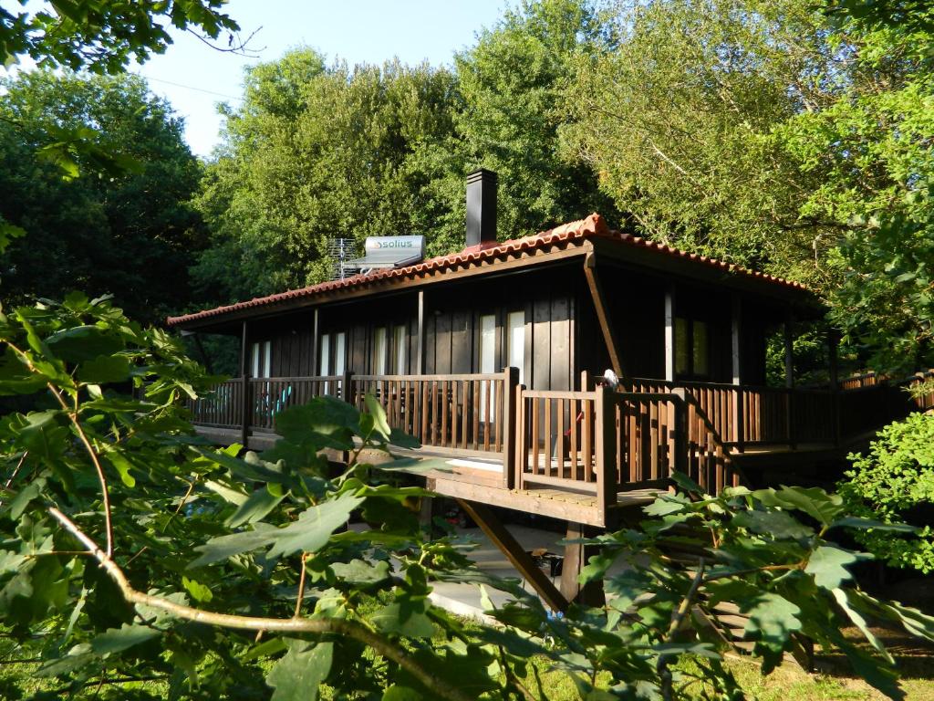 a small cabin with a deck in the woods at Treehouse Quinta Lamosa in Arcos de Valdevez