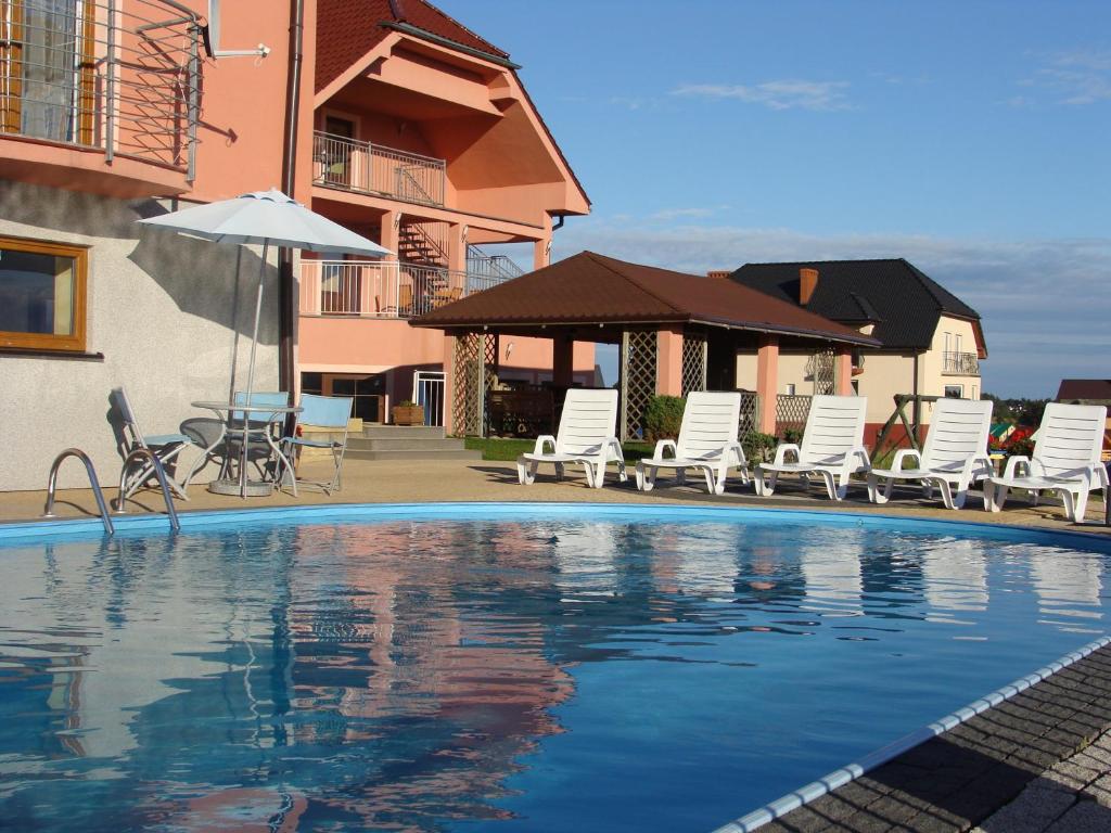 a swimming pool with lounge chairs and an umbrella at Pensjonat Gryf in Jarosławiec