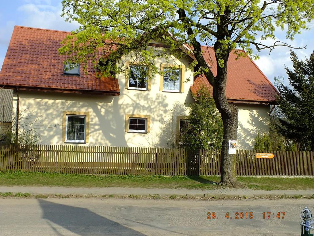 una casa bianca con una recinzione e un albero di Agroturystyka Wielkie Leźno a Wielkie Leżno