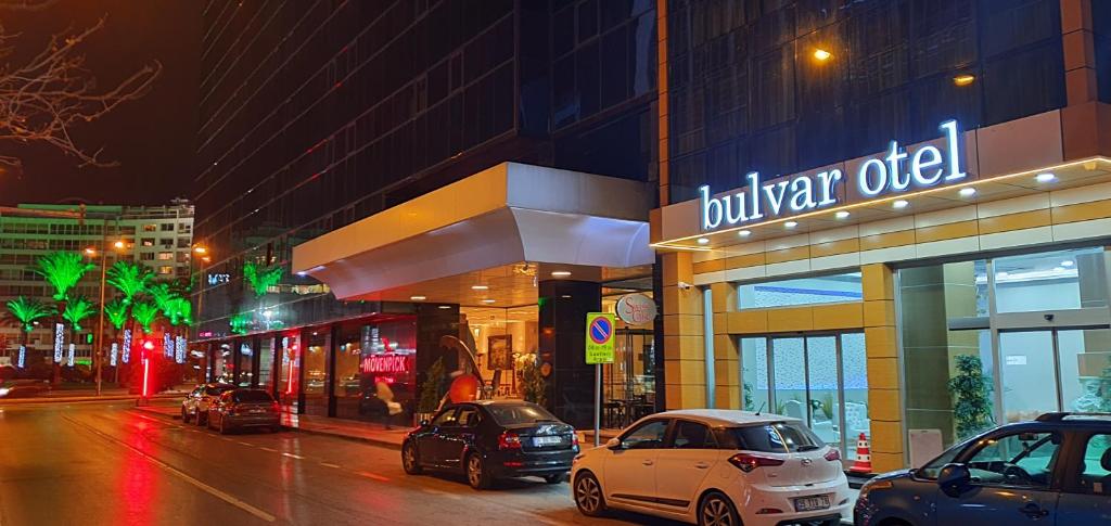 een stadsstraat met auto's die voor een gebouw geparkeerd staan bij Bulvar Hotel in Izmir
