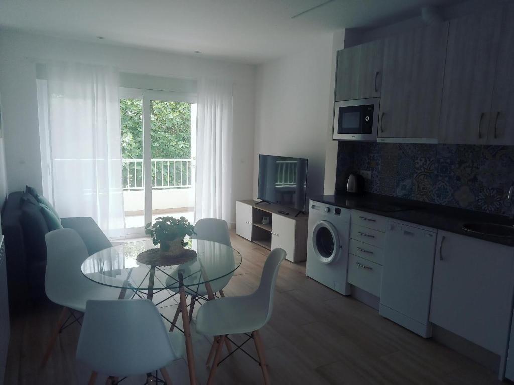 eine Küche mit einem Tisch, Stühlen und einer Mikrowelle in der Unterkunft Apartamento Suances in Suances