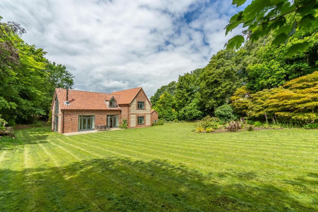 a large grassy yard with a brick house at Woodland Pytchley in West Runton