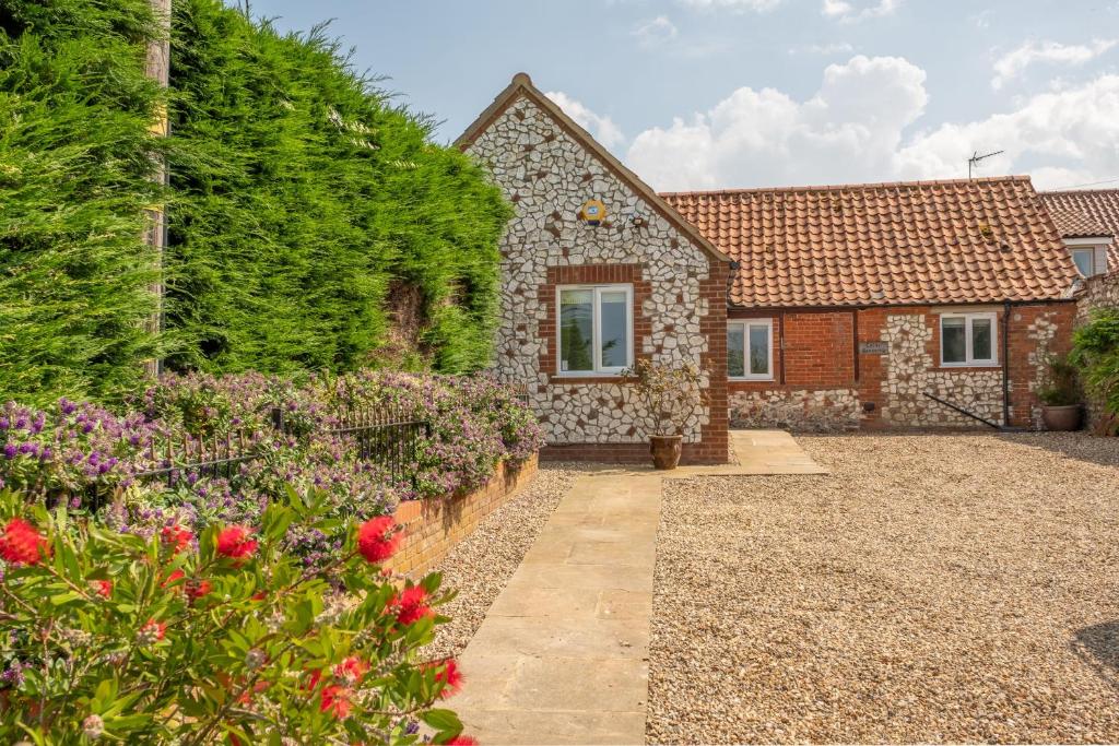 a stone house with a garden in front of it at Castle Bungalow in Thornham