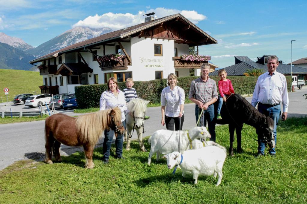 a group of people standing in the grass with animals at Studlerhof in Oberperfuss