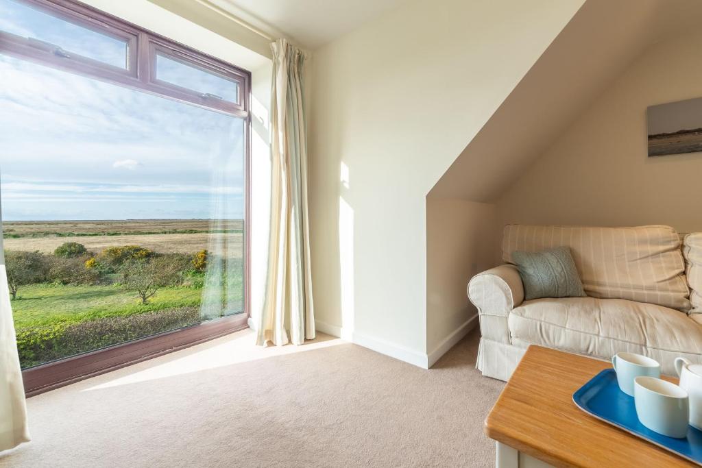 a living room with a couch and a large window at The Saltings Blakeney in Blakeney