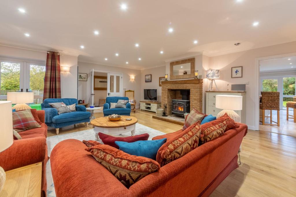 a living room with orange furniture and a fireplace at Waterside in Wiveton