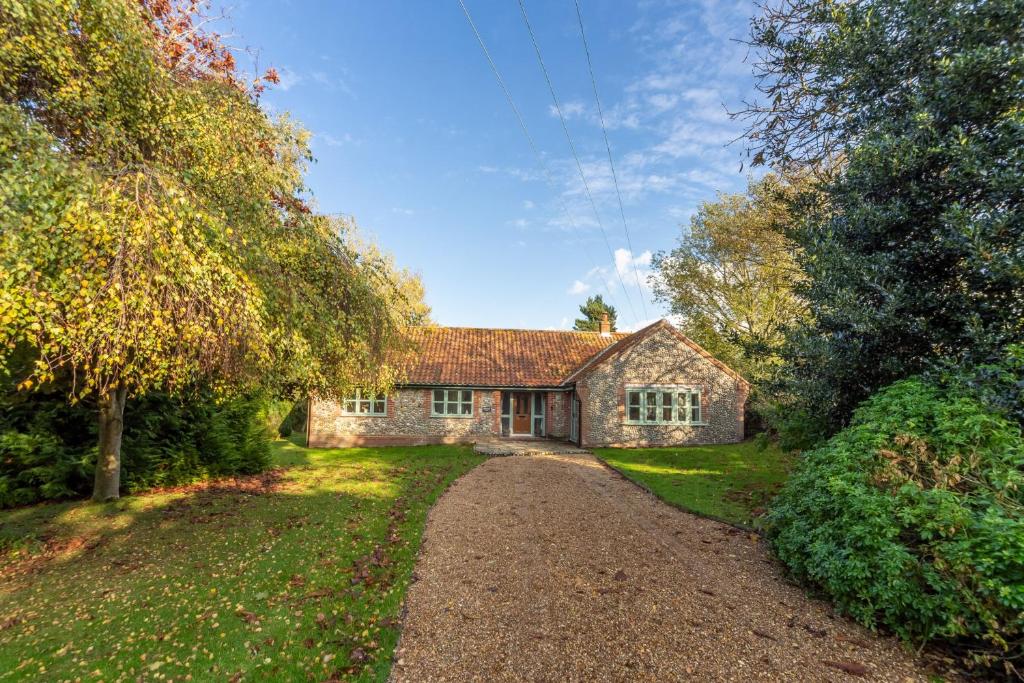 a stone house with a gravel road in front of it at Waterside in Wiveton