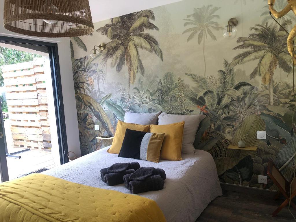 a bedroom with a large bed with a tropical wallpaper at Le paradis des ouches in Aubigny
