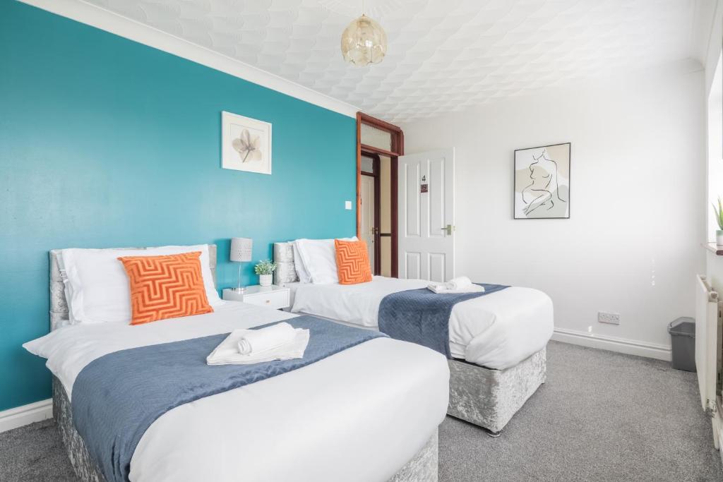 two beds in a room with blue walls at Foxdale's - 5 Bedroom House in Peterborough perfect for groups and families in Peterborough