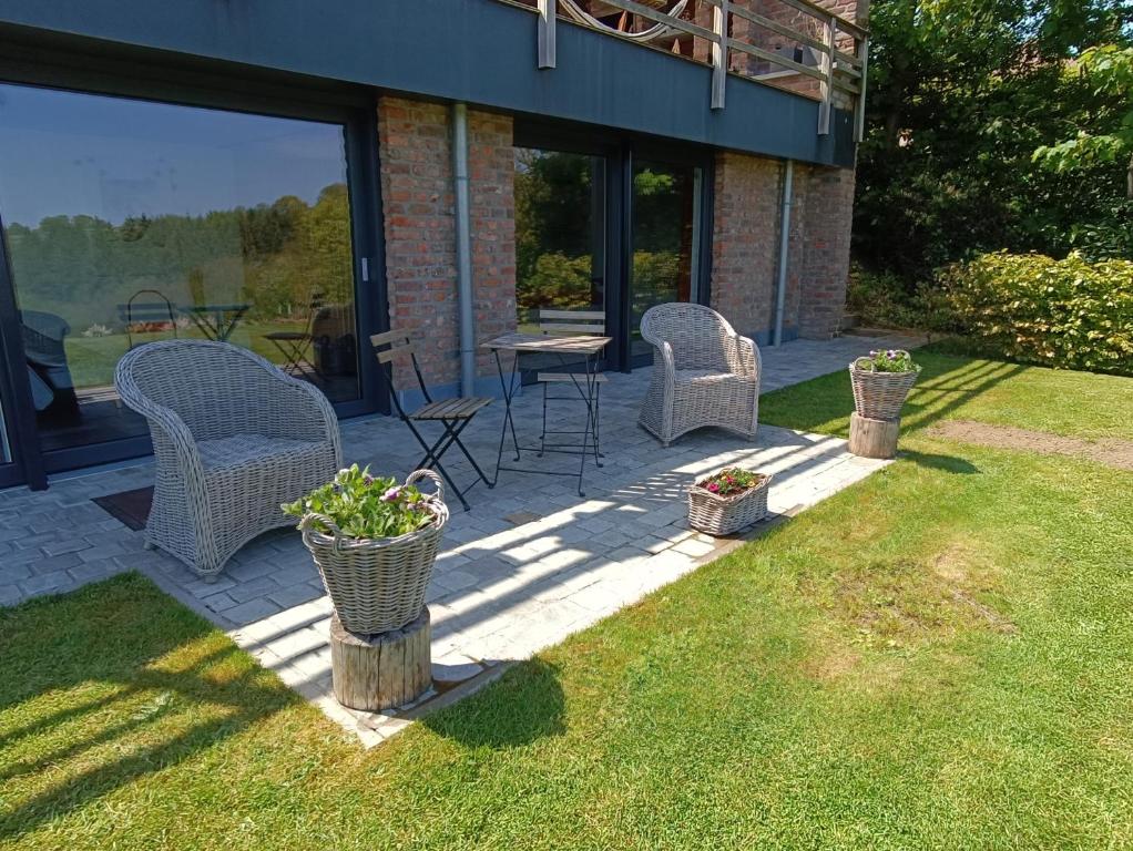 a patio with wicker chairs and a table in a yard at Le Repaire du Nez Rouge in Stavelot