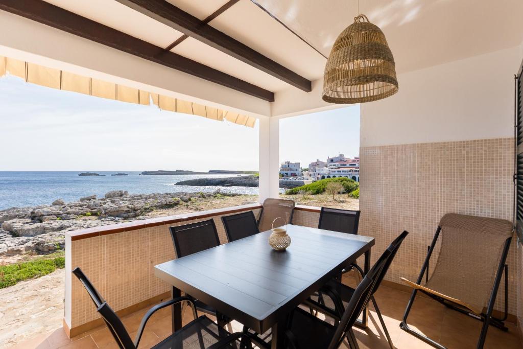 a dining room with a table and chairs and the ocean at Binilaya in Sant Lluis