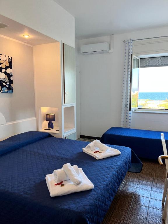 a bedroom with two towels on a blue bed at Hotel La Plancia in Otranto