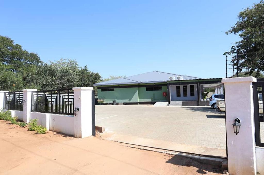 a building with a gate and a parking lot at Amariah Lodge in Kasane