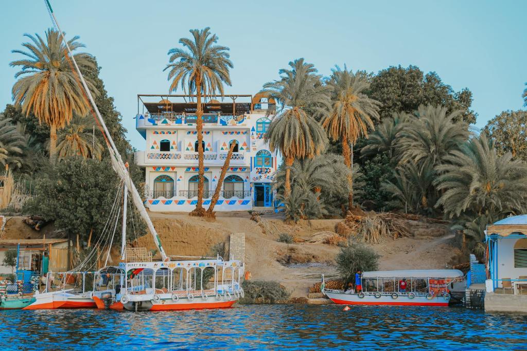 BAYT ZAINA - Nubian hospitality house في أسوان: اثنين من القوارب في الماء امام مبنى