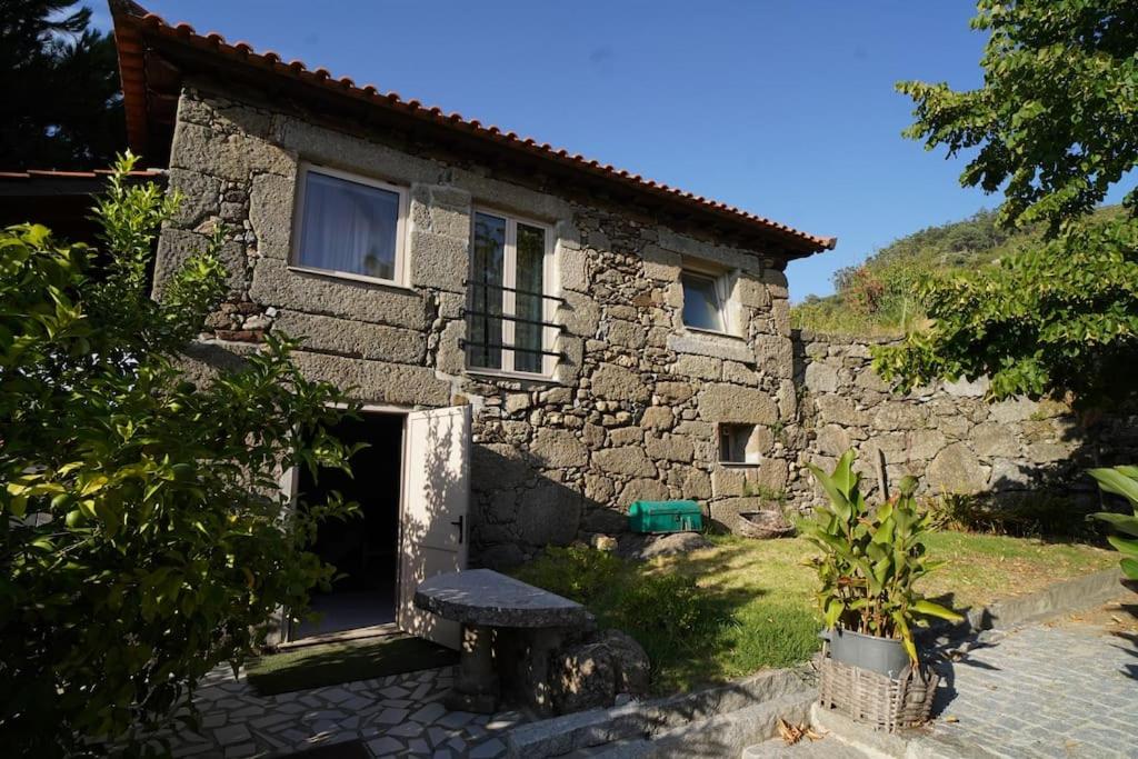 ein Steinhaus mit einer Bank davor in der Unterkunft Lemon Tree Cottage at Terrus Winery in Barrô