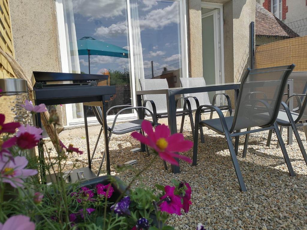 eine Terrasse mit einem Tisch, Stühlen und Blumen in der Unterkunft EssenCiel du lac III in Éguzon-Chantôme