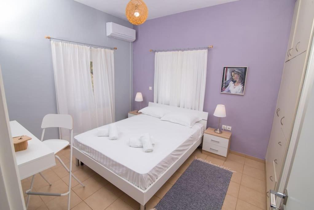 a bedroom with a white bed and a purple wall at Quiet escape in Mikrá Mandínia