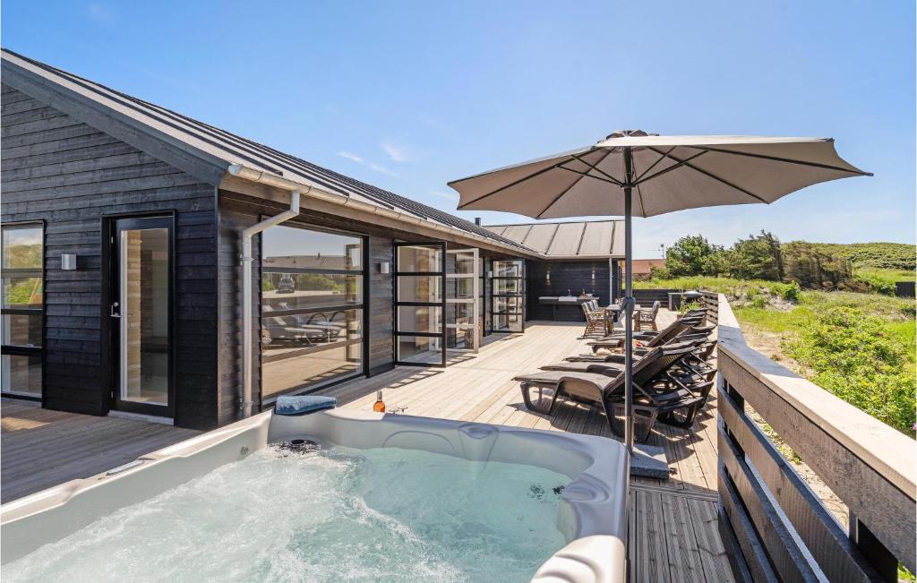 bañera de hidromasaje en una terraza con sombrilla en Amazing Home In Hvide Sande With Outdoor Swimming Pool, en Hvide Sande