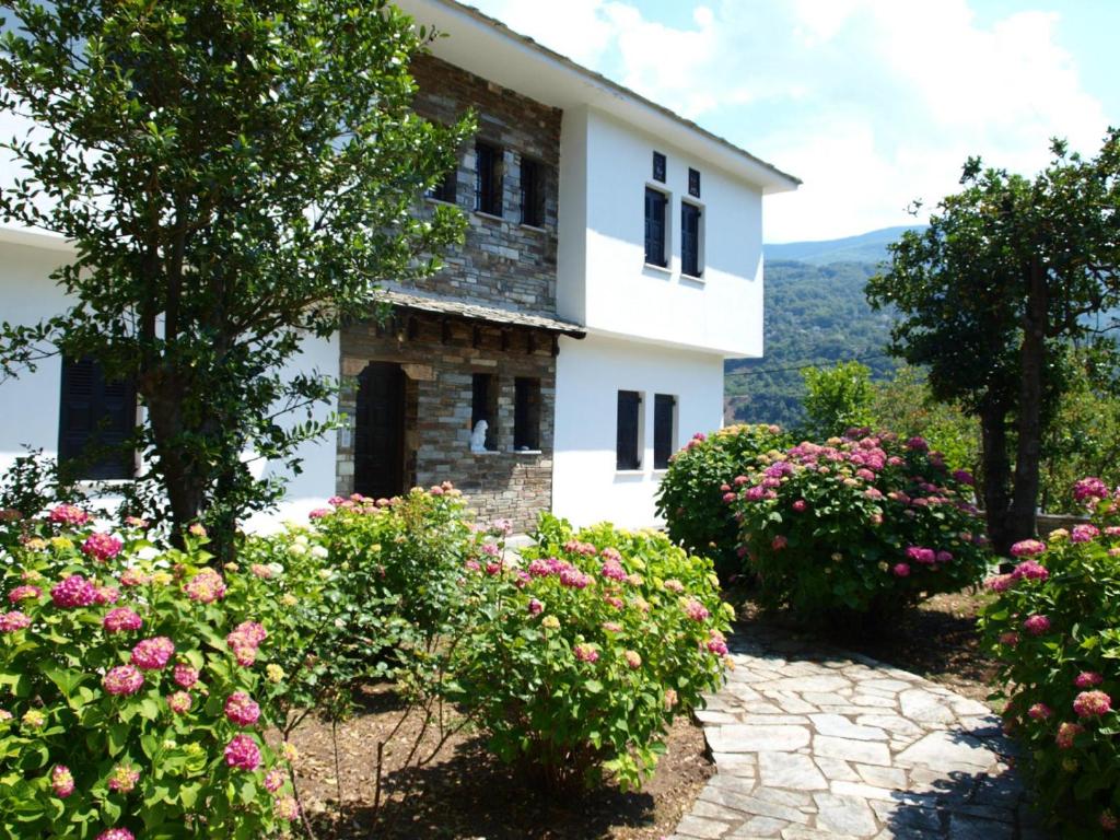 une maison blanche avec des fleurs devant elle dans l'établissement Villa Zina Agios Dimitrios, à Ágios Dimítrios