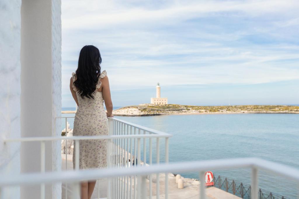 Una mujer parada en un balcón con vistas al océano en Hotel Approdo di Venere en Vieste