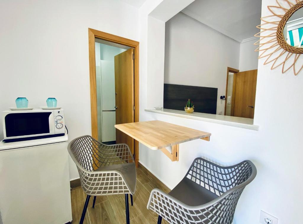 a small kitchen with a table and two chairs at Apartamentos Turísticos Santo Rostro in Chipiona
