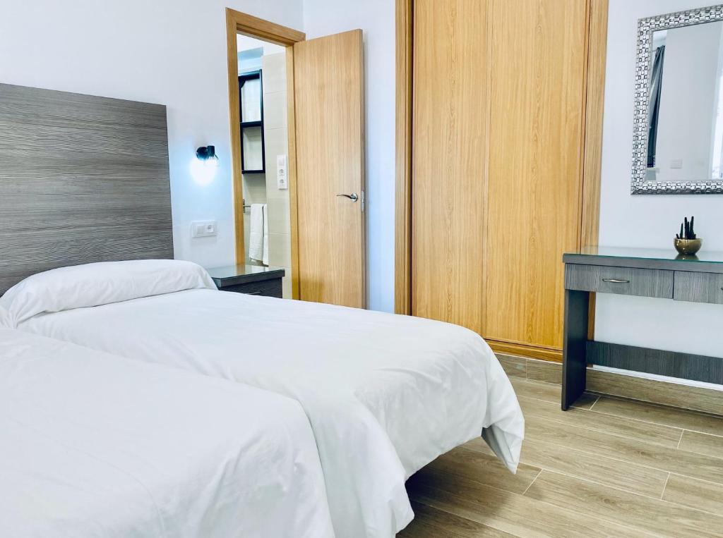 a bedroom with a white bed and a mirror at Apartamentos Turísticos Santo Rostro in Chipiona