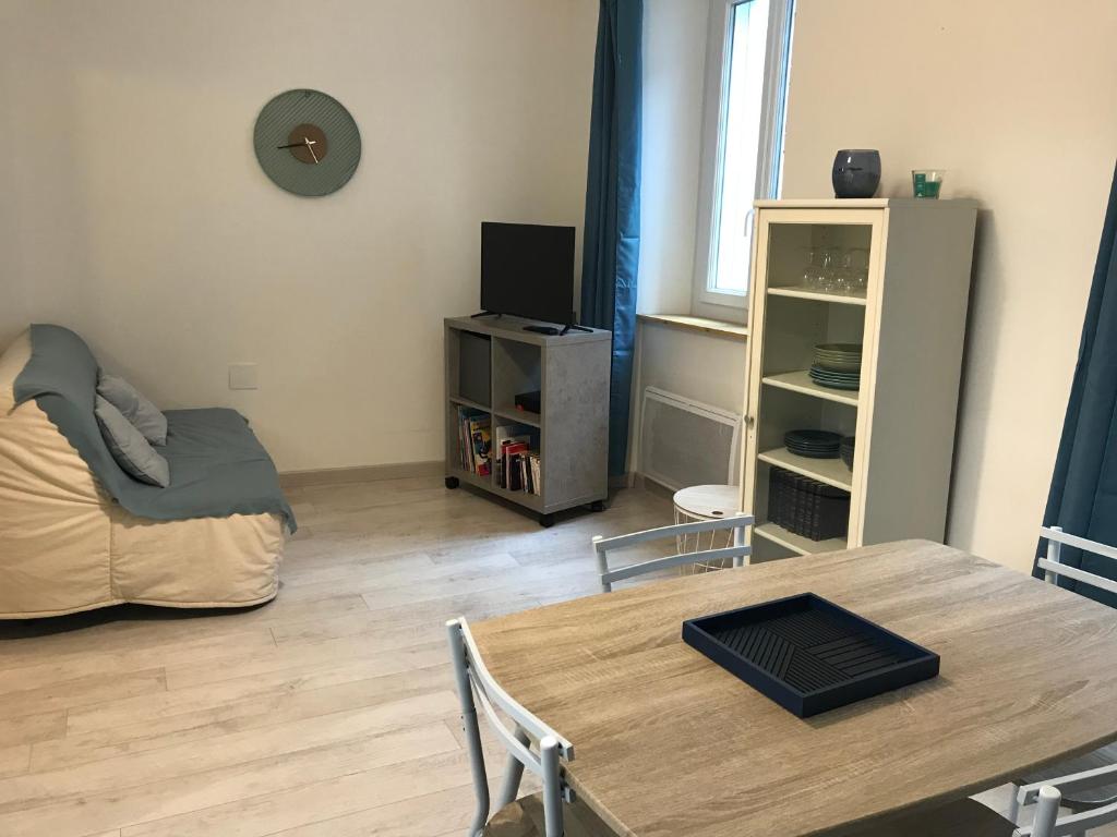 a living room with a table and a bed at Le gite bleu in Ax-les-Thermes