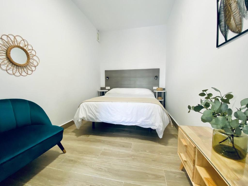 a bedroom with a bed and a blue couch at Apartamentos Turísticos Santo Rostro in Chipiona