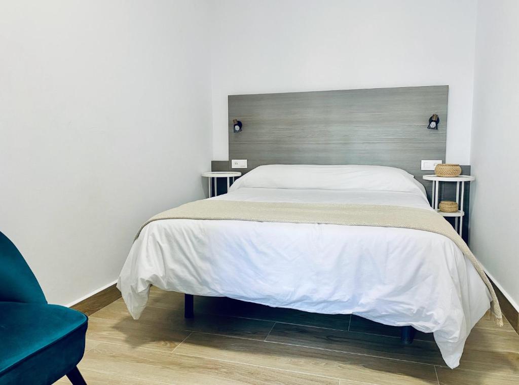 a bedroom with a bed and a blue chair at Apartamentos Turísticos Santo Rostro in Chipiona