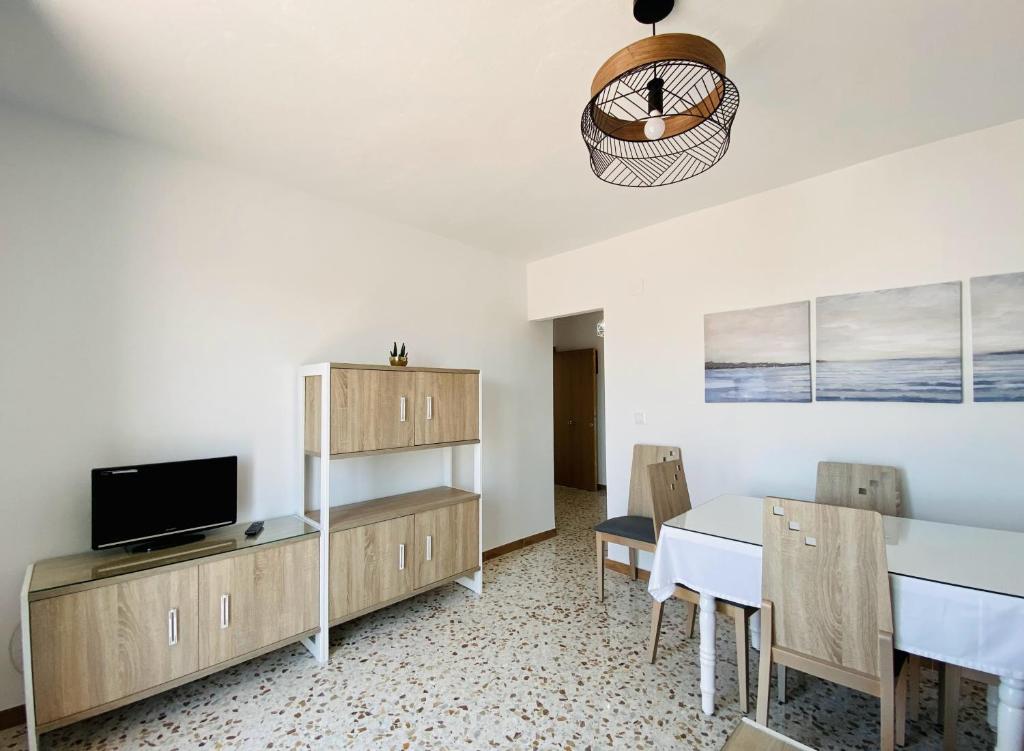 a living room with a dining table and a television at Apartamentos Turísticos Santo Rostro in Chipiona
