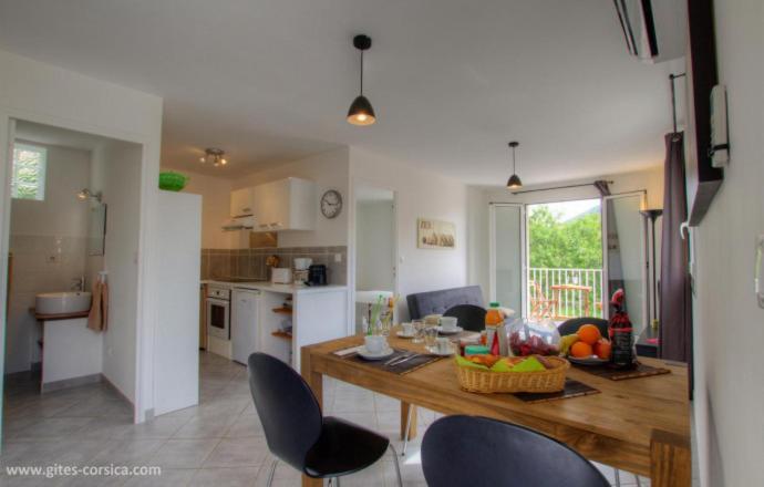 une cuisine avec une table et des chaises dans une pièce dans l'établissement Village Cargese 1, à Cargèse