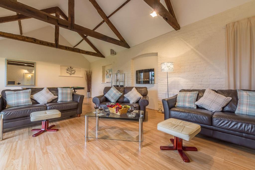a living room with leather couches and a table at Keepers Cottage in Fakenham