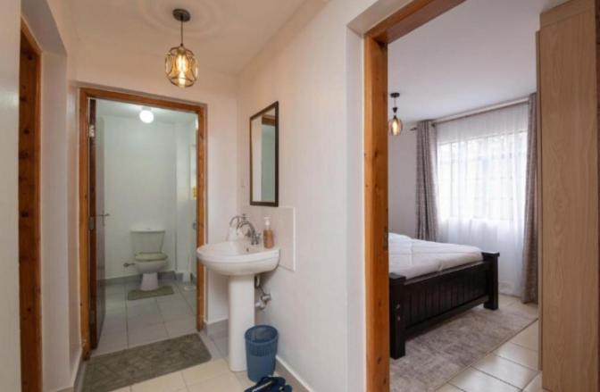 bagno con lavandino, letto e specchio di Phase 2 a Nairobi