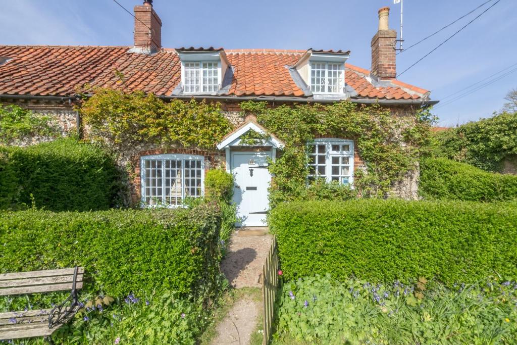 an ivy covered house with a white door at Brooke Cottage in Little Walsingham