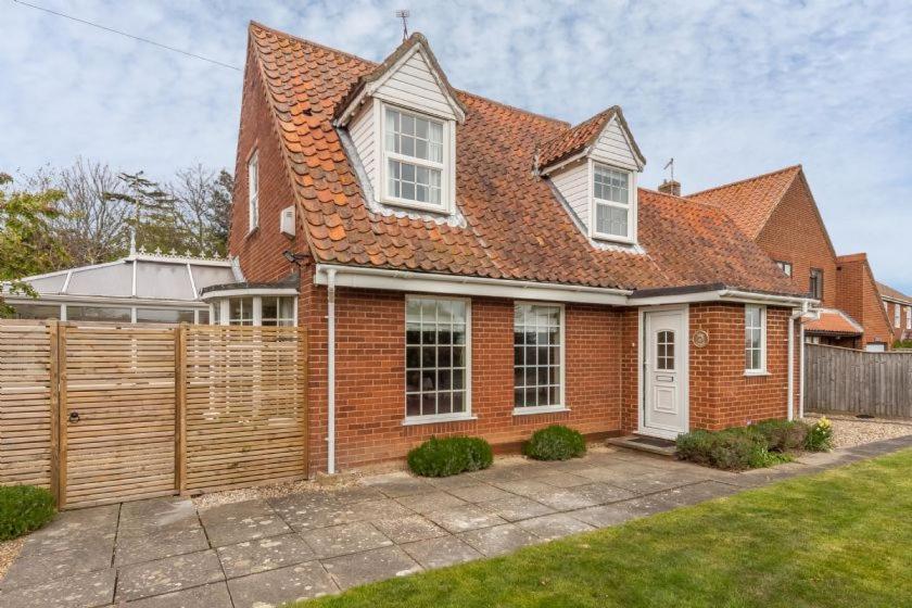 a red brick house with a wooden fence at Forge Cottage in Thornham