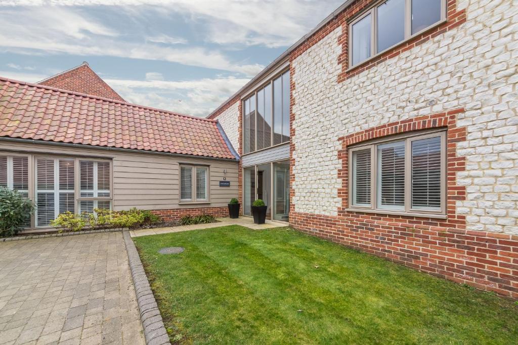 a brick house with a lawn in front of it at Anchorage in Brancaster