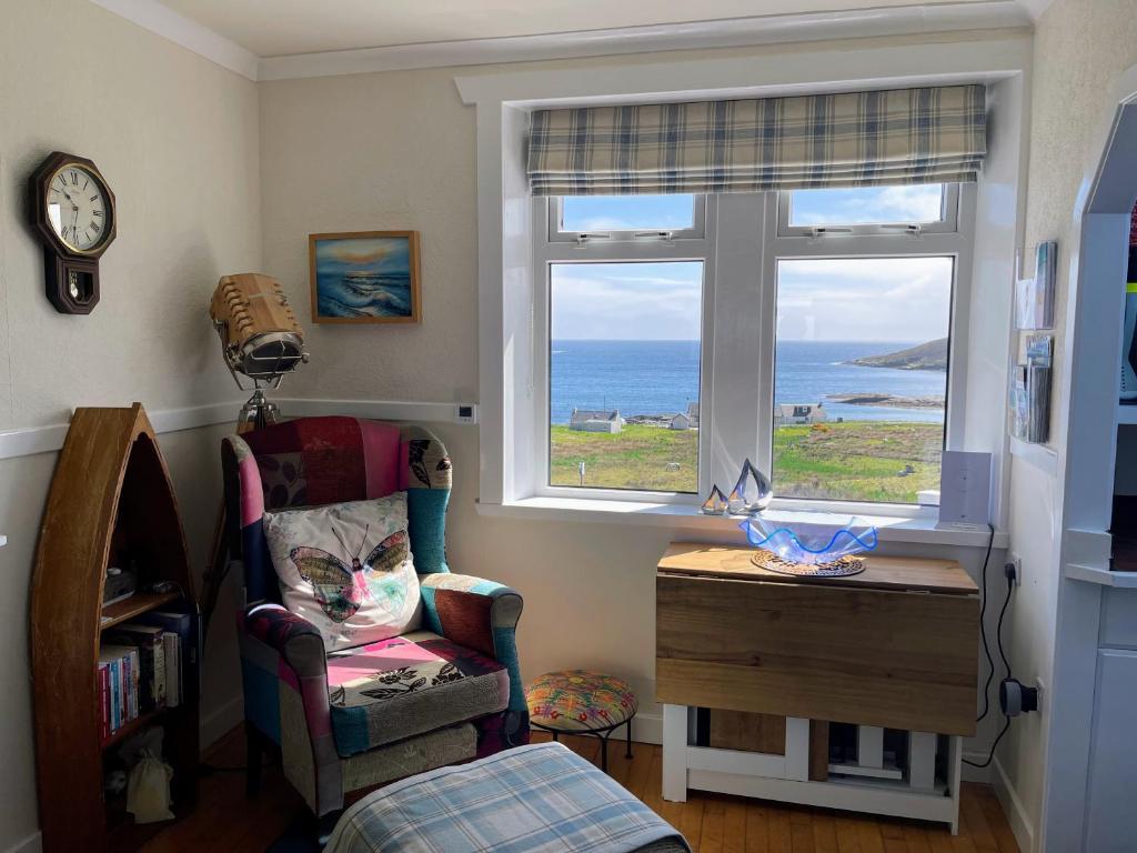 a room with a chair and a window with the ocean at Todday Snug Self Catering Studio in Ersary