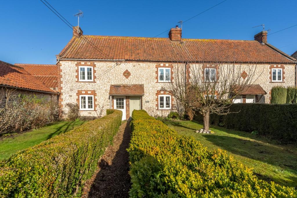 a large brick house with a hedge in front of it at Froggy Cottage in Thornham