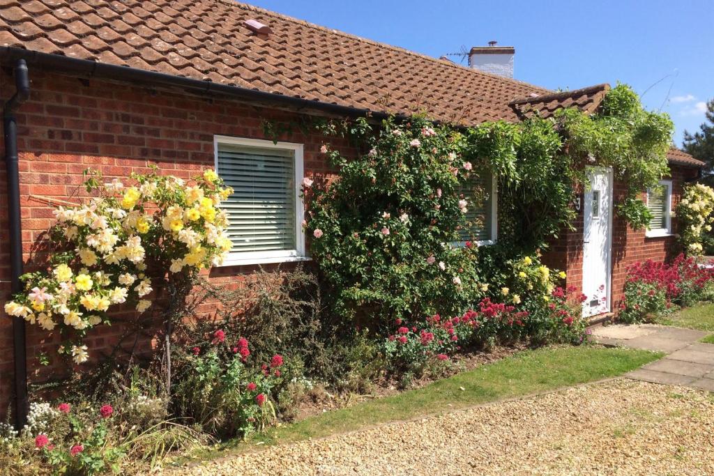 a brick house with flowers in front of it at Sea Wind in Brancaster