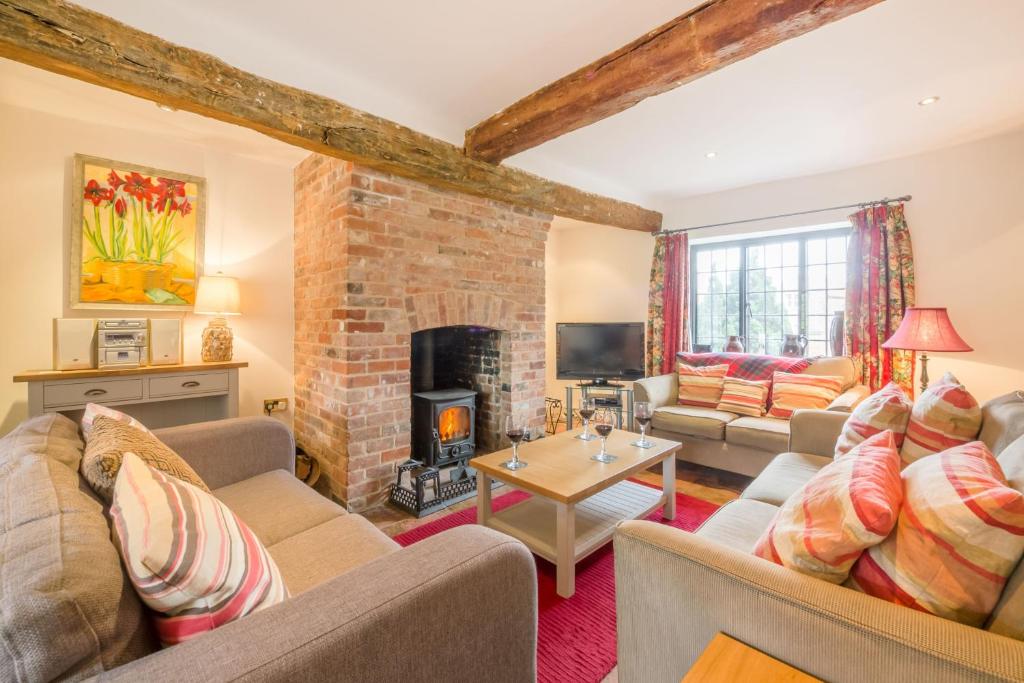 uma sala de estar com sofás e uma lareira em Angel Cottage em Little Walsingham