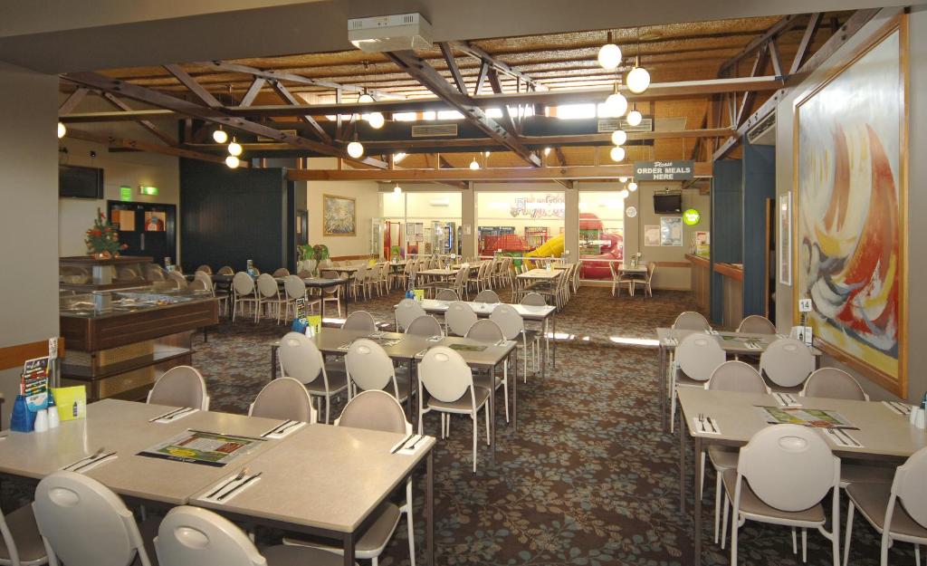 a dining room with tables and white chairs at Argosy Motor Inn in Devonport