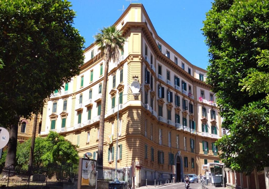 um grande edifício com uma palmeira em frente em Amedeo Suite - Il salotto di Napoli em Nápoles