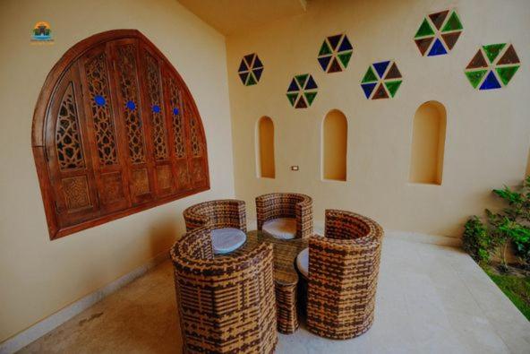 a room with wicker chairs and a wall with a door at Tunis castle in ‘Izbat an Nāmūs