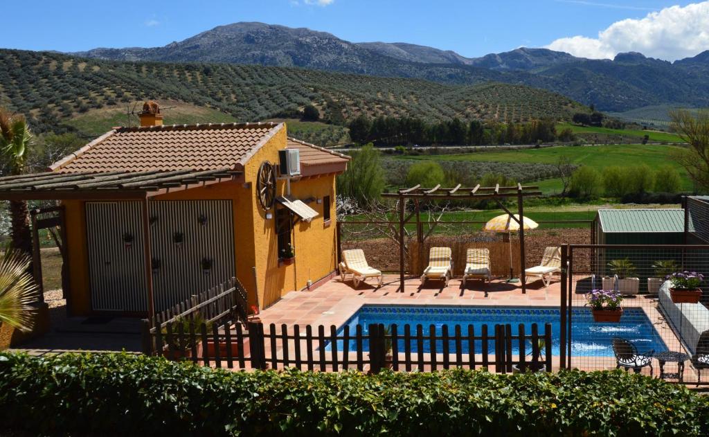 a villa with a pool and mountains in the background at Cortijo Petra in Villanueva del Rosario