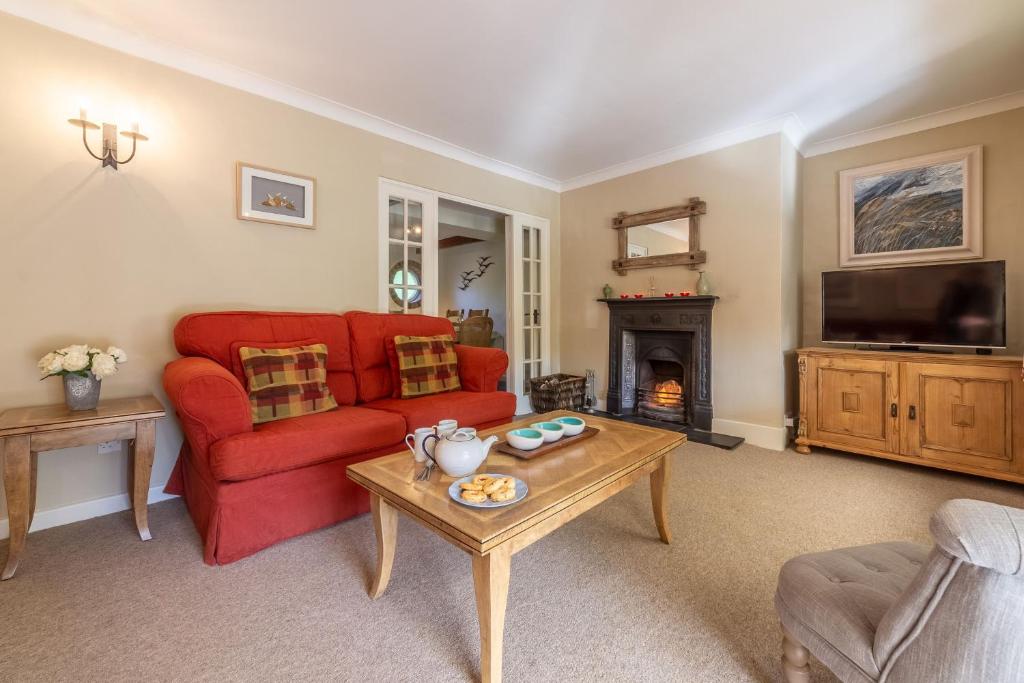 a living room with a red couch and a fireplace at Columbine Cottage in Holme next the Sea