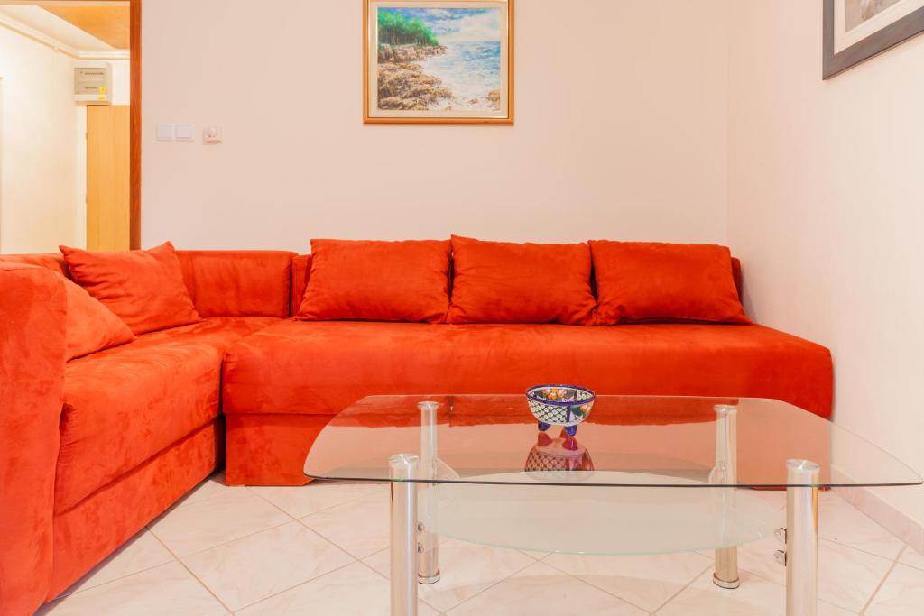 sala de estar con sofá naranja y mesa de cristal en Apartment Aldo, en Pula
