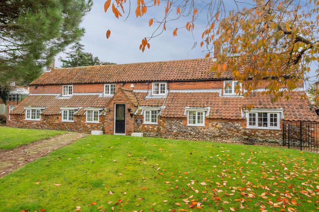 an old brick house with a lawn in front of it at Cheney Hollow in Heacham